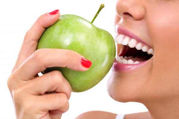 closeup of the face of a woman eating a green apple, isolated against white background